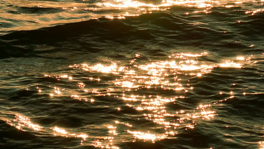 Aerial view reveals the smooth and flowing patterns of the water, with hints of golden reflection that create a rich, textured scene, evoking elegance and calm.
