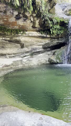 Small waterfall cascading into a clear, shallow pool with visible rocks at the bottom. Trees and vegetation surround the rocky area under a bright sky. Natural freshwater scene.
So paceful. 