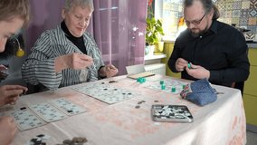 An elderly woman pensioner plays Bingo. A grandmother with her happy family plays board game at home. Lotto on table. Fun time together. - Powered by Shutterstock - Get 15% off with code: PIKWIZARD15