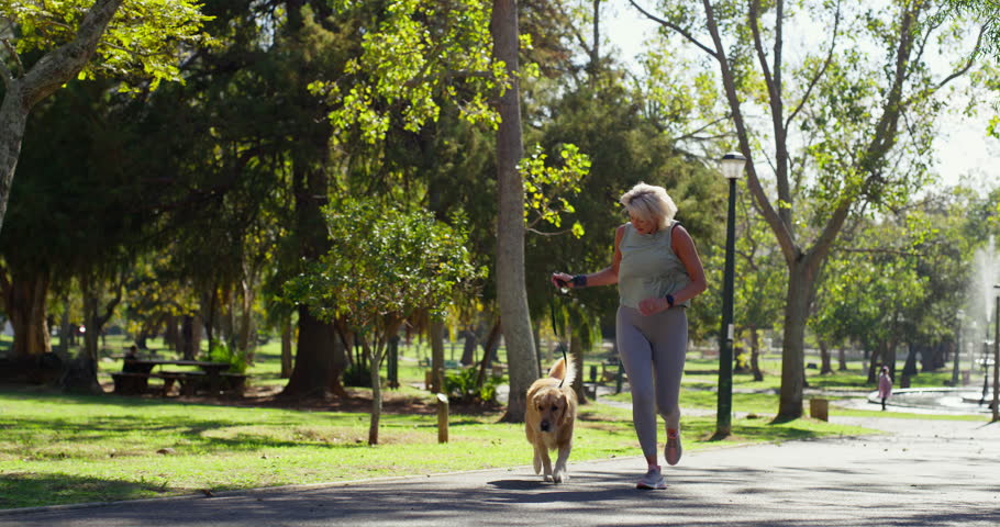 Mature woman, running and exercise with dog for fitness or outdoor workout at park in nature. Active, female person or runner with pet animal for cardio, jog or bonding together on path at forest