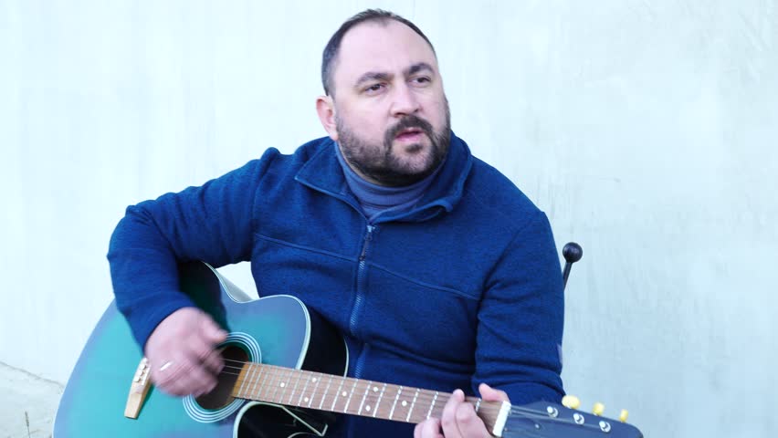Man plays guitar outdoors at the backyard
