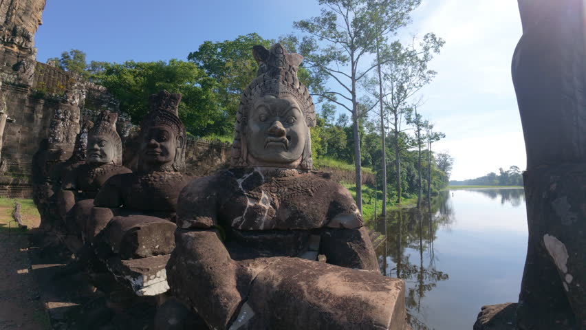 Detailed close-up of ancient stone carvings with clear textures on the stone structures, set against a bright blue sky. Cambodia Angkor Wat Temple
