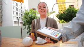 Happy woman is engaging in a delightful moment while processing a payment with her credit card at a charming outdoor cafe table, enjoying the company and the excitement of a busy interaction. High - Powered by Shutterstock - Get 15% off with code: PIKWIZARD15