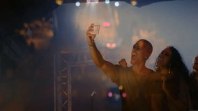 group of friends capturing selfie with phone on stage for event marketing with floating spotlights. Party, celebration, camaraderie, nightlife, entertainment, vibrance, youth - Powered by Shutterstock - Get 15% off with code: PIKWIZARD15