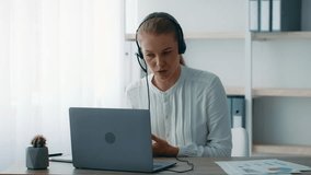 A young businesswoman with a headset communicates during a virtual meeting in a bright, contemporary office. She displays an engaged and focused expression while using her laptop. - Powered by Shutterstock - Get 15% off with code: PIKWIZARD15