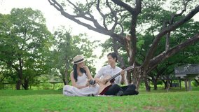 Asian young couple spend time on romantic date in the outdoors garden. Attractive romantic man and woman feel happy and relax, play guitar and taking photo while having picnic together at public park. - Powered by Shutterstock - Get 15% off with code: PIKWIZARD15