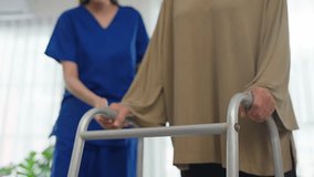 Close up of senior woman patient doing physical therapy with caregiver. Attractive specialist carer help and support elderly mature grandma practice walking slowly with walker at nursing home care. - Powered by Shutterstock - Get 15% off with code: PIKWIZARD15