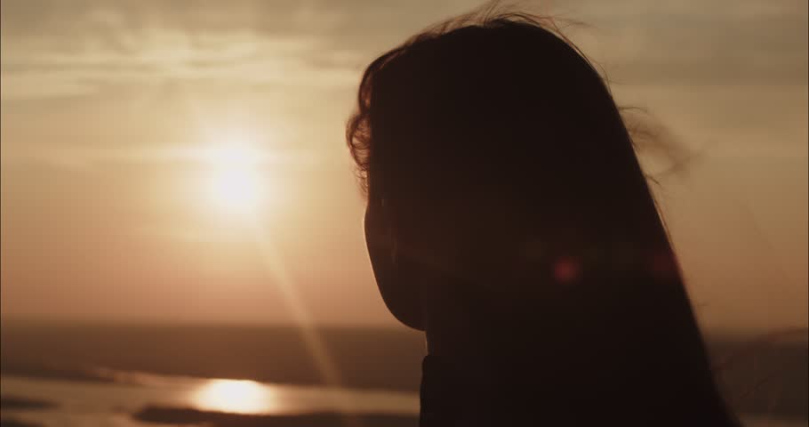 Young woman watching golden sunset over river