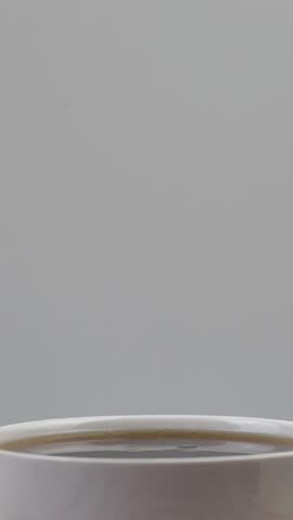 slow motion video of three brown sugar cubes falling into a cup of black tea