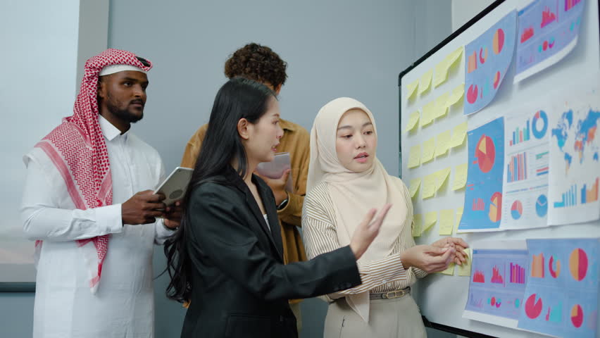 Diverse business team working on whiteboard at office,Two female chief analyst holding meeting with two man business showing digital interactive whiteboard with charts, data and statistics at briefing