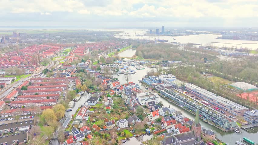 Aerial: cityscape, Amstel river and buildings during the day in Amsterdam, Netherlands, jib down drone shot