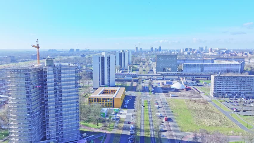 Aerial: cityscape, trains and buildings during the day in Amsterdam, Netherlands, crane up drone shot