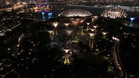 Cinematic drone orbit shows Singapore’s Supertree Grove illuminated at Gardens by the Bay, glowing against the night sky with shifting light patterns and distant city skyline. - Powered by Shutterstock - Get 15% off with code: PIKWIZARD15