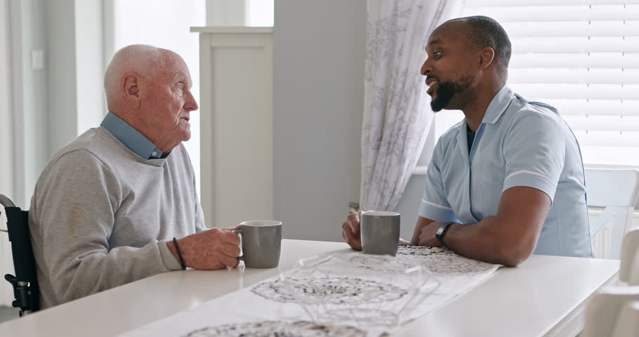 Support nurse and old man in a wheelchair talking with support, care or healthcare consulting in retirement. Elderly, caregiver and person with a disability and help with kindness or coffee in home