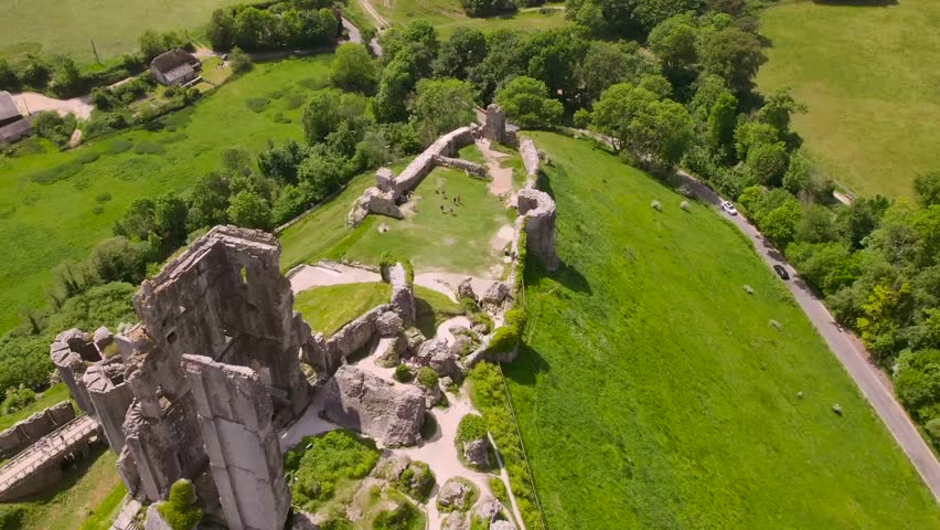 High-angle drone view of Corfe Castle showing the interior ruin layout and nearby countryside in Dorset, England, on a sunny summer day