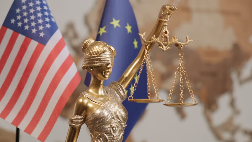 Statue of Justice with United States of America flag and European Union flag in background in office
