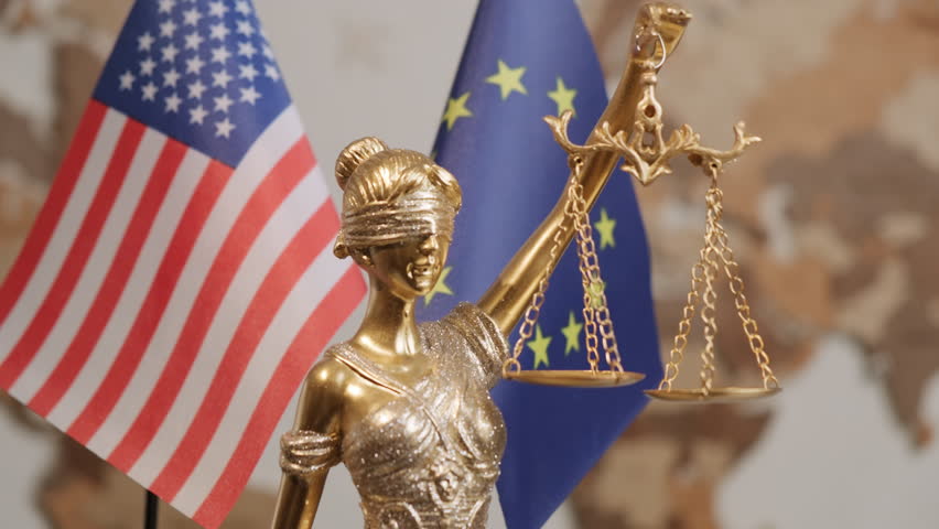 Statue of Justice with United States of America flag and European Union flag in background in office