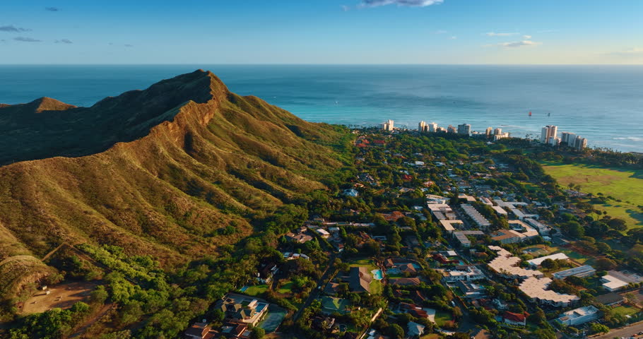 Flight above the cityscape in the lush greenery at the foot of Diamond Head Crater. Honolulu, Hawaii, USA. Pacific Ocean waterscape at backdrop.