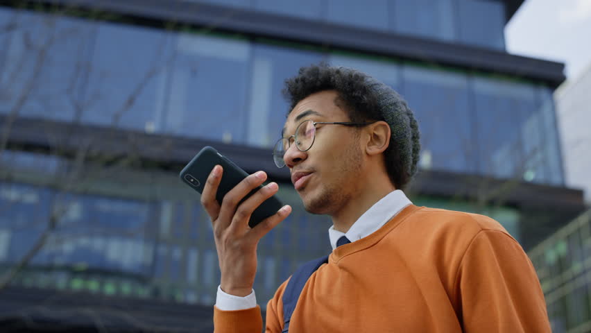 Student recording voice message outdoors near office building