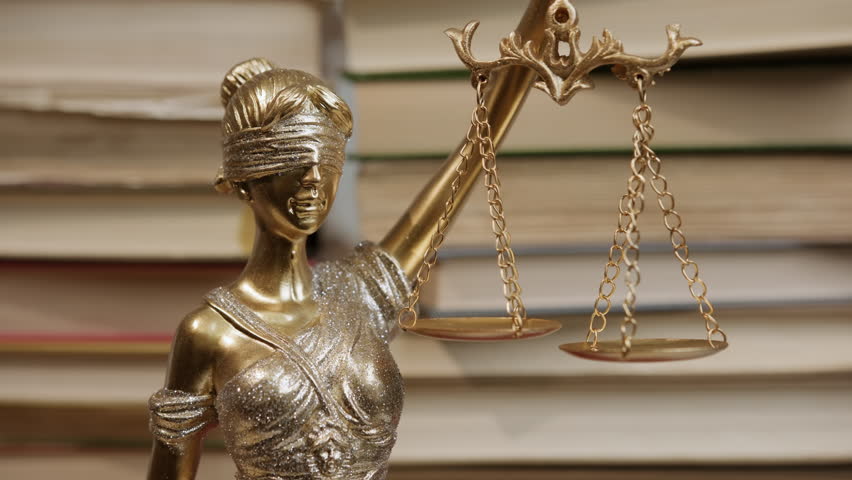 Statue of Justice with flag of United States of America on background of stacks of law books in legal setting