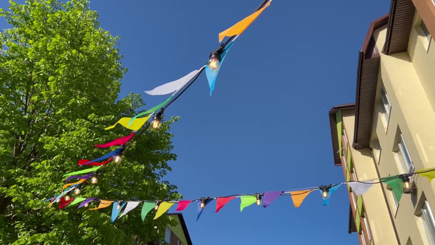 A windy day. Colored flags of cafes. A sunny city. Decorations on the street. Street cafes. 