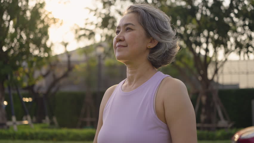 Asia adult aged people middle age mindful happy old woman open arm yoga deep calm stress relief outdoor nature public park sun light self love relax elder aging life asian female mental health care.