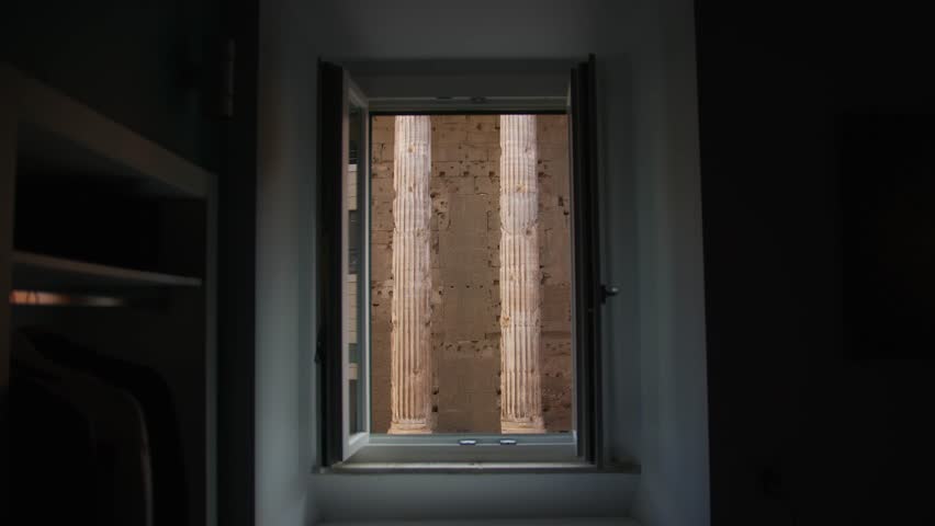 A person gazing out a window at ancient Roman architecture near the Pantheon