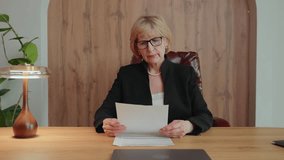 A 60-year-old blonde woman working remotely reads a document, frowns slightly, then crumples the paper and throws it away. Her reaction shows high standards and leadership control. 4k footage - Powered by Shutterstock - Get 15% off with code: PIKWIZARD15
