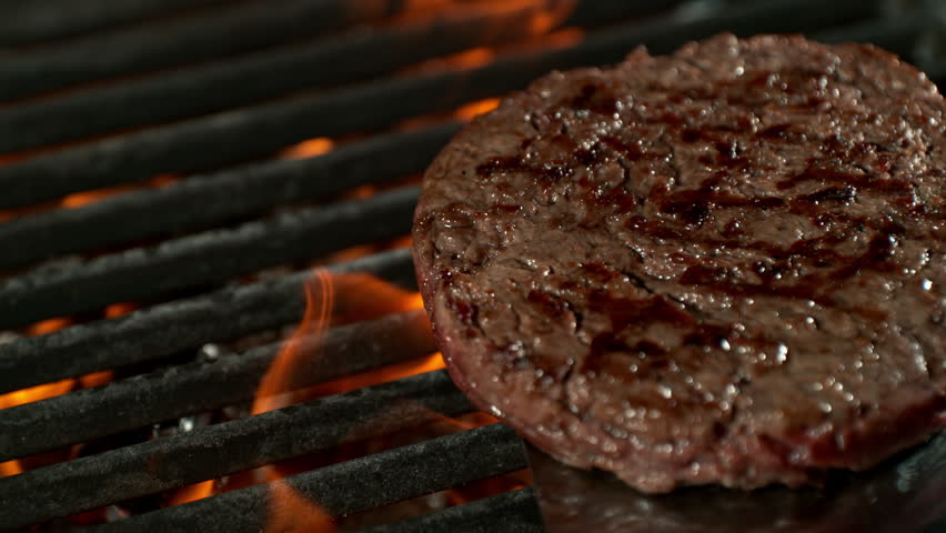 Super Slow Motion Shot of Flipping Hamburger Meat on Hot Grill with Flames and Embers at 1000fps.