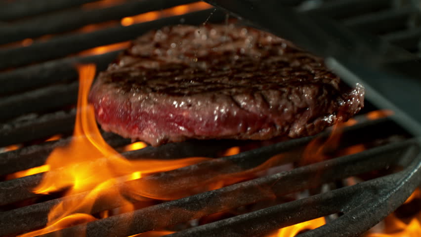 Super Slow Motion Shot of Flipping Hamburger Meat on Hot Grill with Flames and Embers at 1000fps.