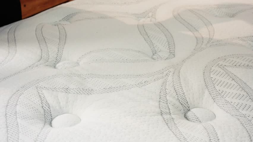 Hand sinks into plush mattress in slow motion revealing responsive foam