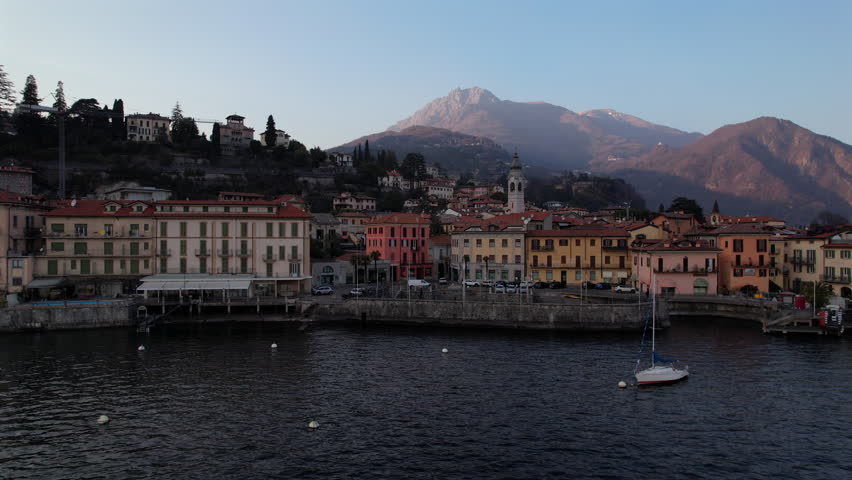 A cinematic drone reverse reveals Menaggio’s charming waterfront along Lake Como, with pastel architecture and alpine peaks unfolding in the background of Northern Italy.