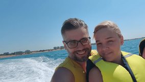 Happy family shoot yourself on action camera while riding banana boat on blue sea on summer day. Water entertainment attraction. Travel holiday tourism - Powered by Shutterstock - Get 15% off with code: PIKWIZARD15