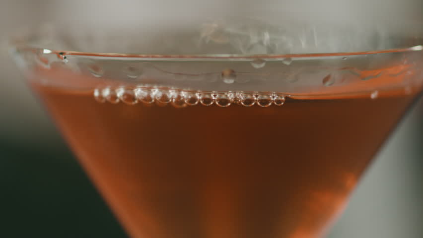 Close-up of an elegant martini glass with a carefully placed metal toothpick, garnished with a cherry.