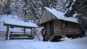 Snowy retreat in a cozy log cabin surrounded by winter woods and a person enjoying the serene landscape. Winter Hiking in Carpathian Mountains, Ukraine - Powered by Shutterstock - Get 15% off with code: PIKWIZARD15