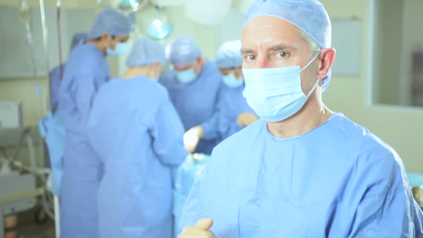 Close up male Caucasian senior hospital surgeon with skilled multi ethnic medical team performing surgery in sterile surroundings | Shutterstock HD Video #3781733