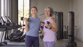 Young adult child and middle age old mum smile look at camera gym workout body weight picking up arm lift dumbbell. Health care older mom asia elder people happy protect aging life sport build muscle. - Powered by Shutterstock - Get 15% off with code: PIKWIZARD15