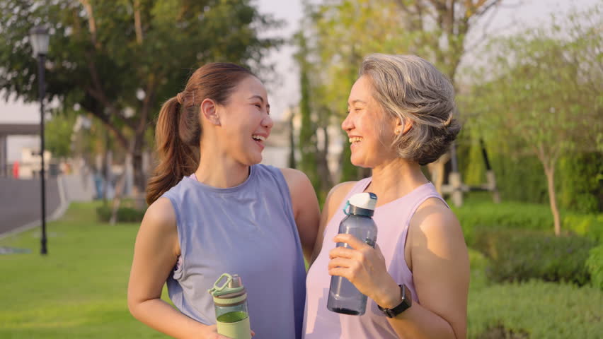 May Mother's day young adult child smile look at camera cuddle hug mature middle age old mum at outdoor green public park nature. Love kiss care mom asia elder people happy enjoy family aging life.