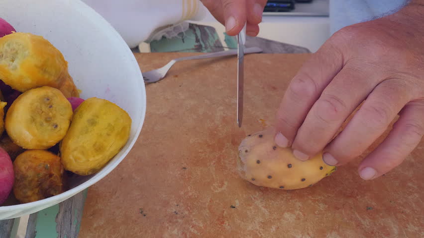 Hands peeling and cutting prickly pears on a wooden board, preparing the sweet fruit. Video accelerated