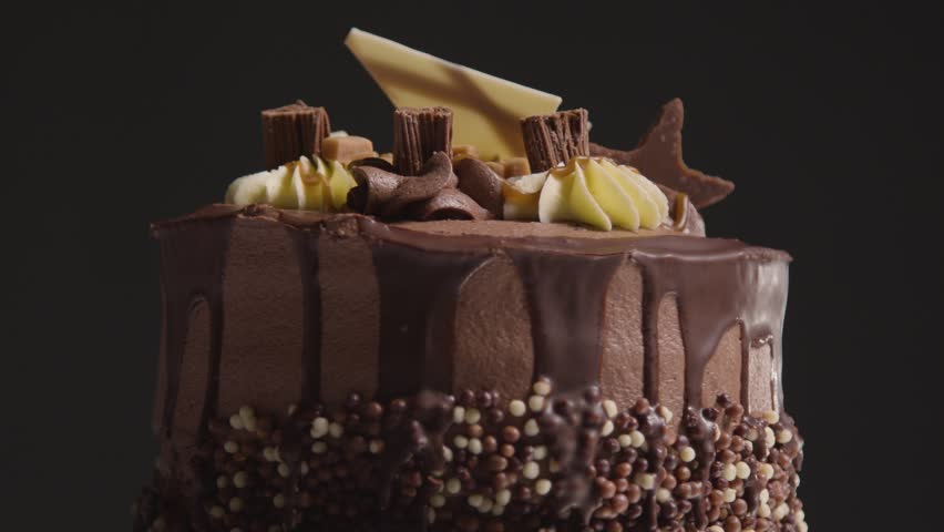 close up studio shot of freshly baked and decorated chocolate celebration cake revolving against black background stock video