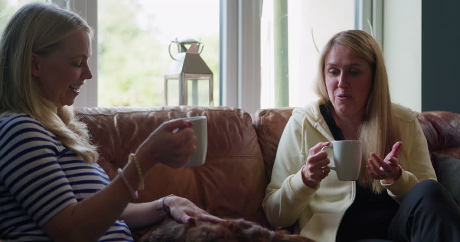 Coffee cup, laughing friends and women conversation, talking and speaking in morning chat, communication or discussion. Pet dog, share funny news and home people consulting, gossip or drink green tea