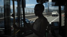 A dark silhouette of a young woman stands in a city bus, holding a smartphone while illuminated by passing highway lights. Through the window, a busy urban freeway pulses with nighttime traffic - Powered by Shutterstock - Get 15% off with code: PIKWIZARD15