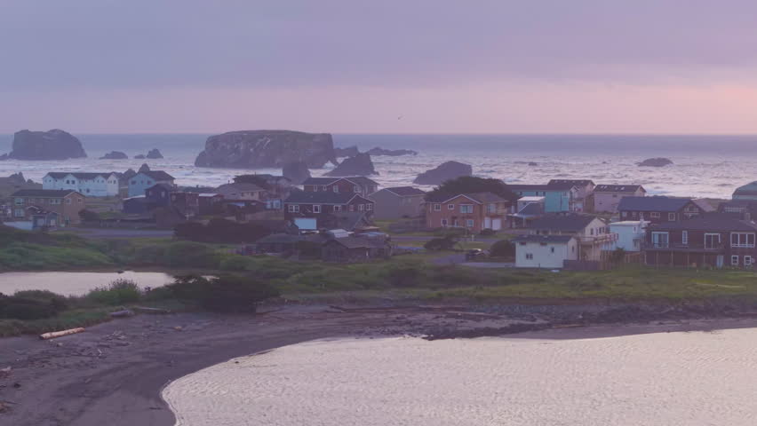Real estate homes by the Coquille River and Pacific Ocean in Bandon, Oregon. Drone tracking shot.