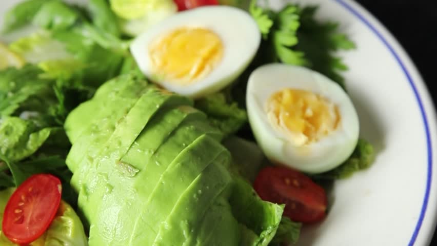 Salad avocado, boiled egg, tomato, green leaf lettuce, vegetable dish fresh delicious gourmet food background on the table rustic food top view copy space