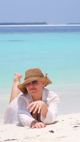 woman relax on summer resort, woman smiling while lying on sandy beach wearing a straw hat and white shirt, bright sunny tropical atmosphere in maldives, island vacation, summer happiness
