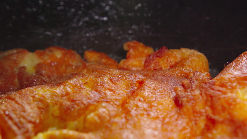 Close-up shot of a traditional Thai omelet frying in hot oil, showing bubbling oil and crispy texture on the egg surface, cooked in a wok.