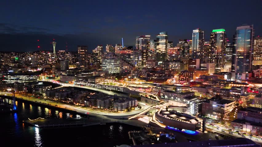 A breathtaking aerial night view of downtown Seattle, Washington, showcasing the illuminated skyline and iconic skyscrapers. Glowing Seattle Great Wheel. Seattle at night. Top cinematic aerial view