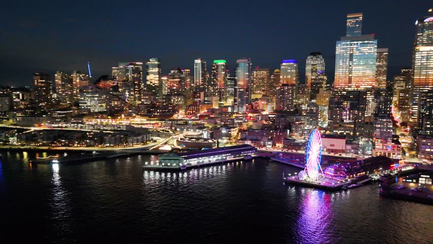 A breathtaking aerial night view of downtown Seattle, Washington, showcasing the illuminated skyline and iconic skyscrapers. Glowing Seattle Great Wheel. Seattle at night. Top cinematic aerial view