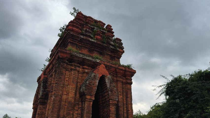 Historic red-brick Binh Lam Champa Tower in Vietnam stands tall against a moody sky, evoking a sense of mystery and ancient grandeur, ideal for travel or history projects.
