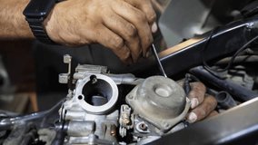 Male hands of repairer fixing motor of motorbike using tool at workplace. Arms of professional mechanic repairing engine of motorcycle at workshop. Adult repairman working at garage. Slow motion - Powered by Shutterstock - Get 15% off with code: PIKWIZARD15